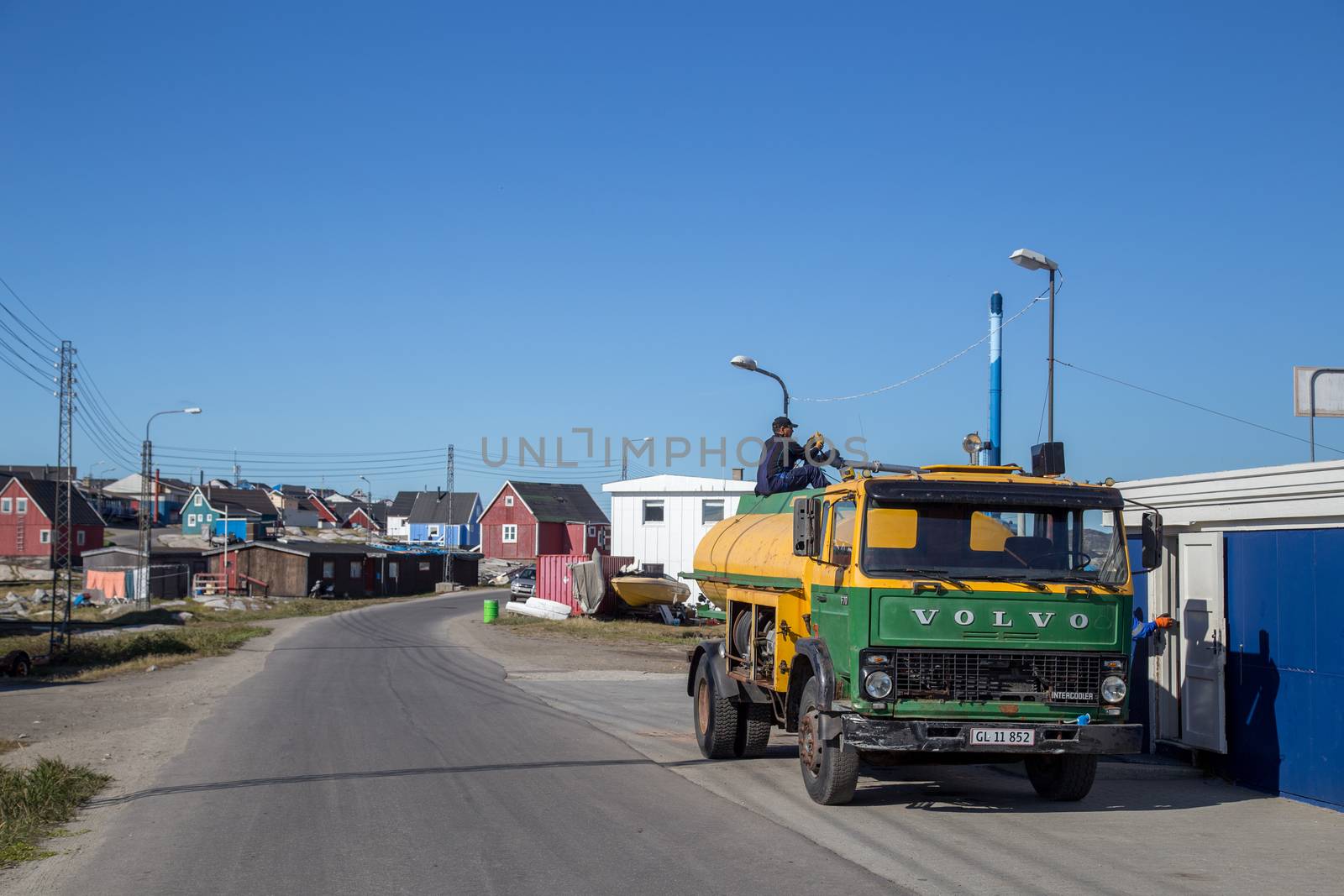 Qeqertarsuaq, Greenland - July 6, 2018: A worker sitting on a fuel truck. Qeqertarsuaq is a port and town located on the south coast of Disko Island.