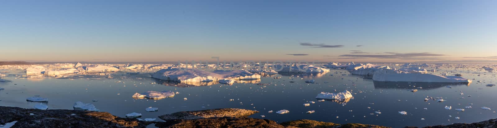 Ilulissat, Greenland - July 7, 2018: Panoramic view of the Ilulissat Icefjord during midnight sun. Ilulissat Icefjord was declared a UNESCO World Heritage Site in 2004.