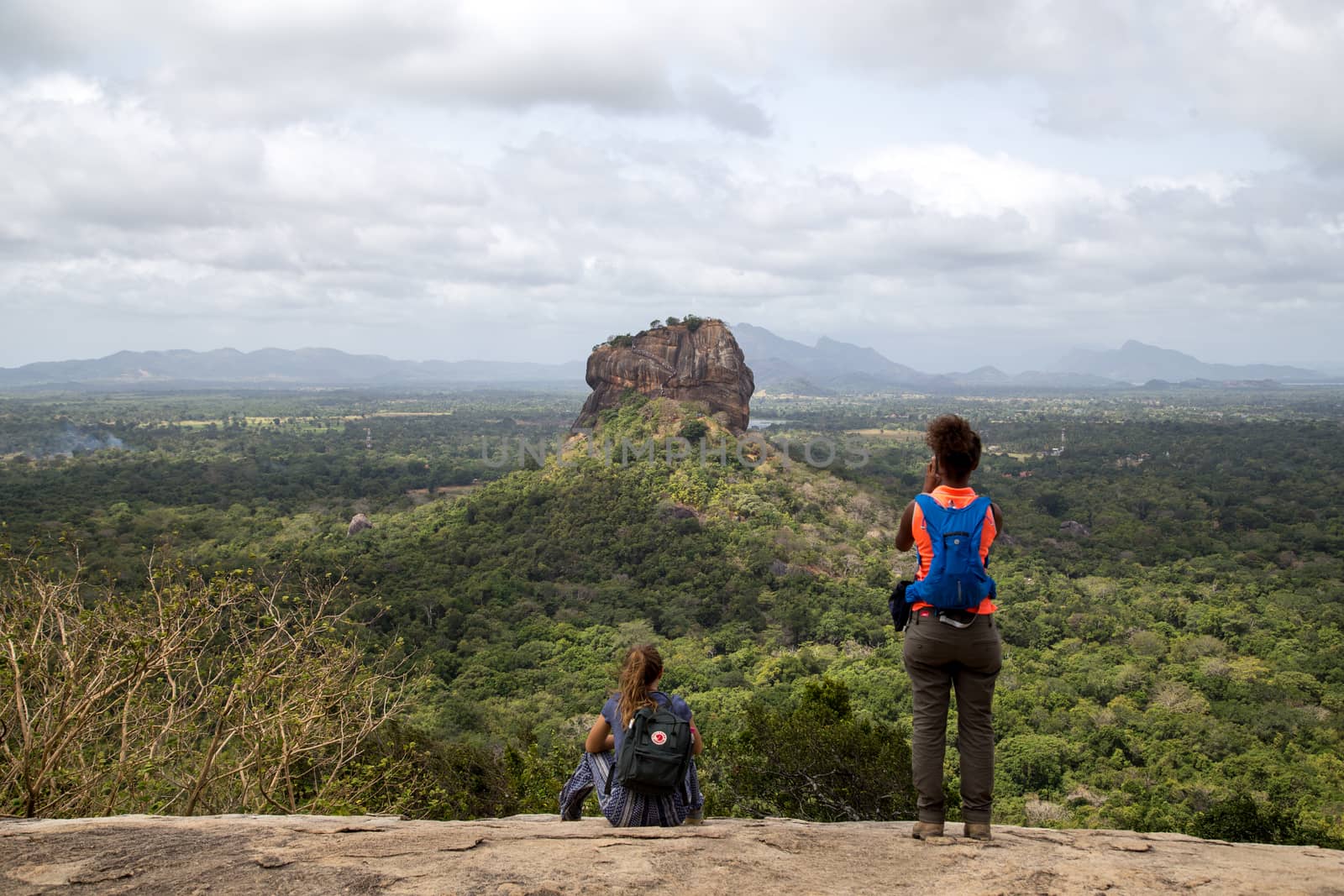 Sigiriya, Sri Lanka - August 17, 2018: Two tourists admiring the Lion Rock in the distance