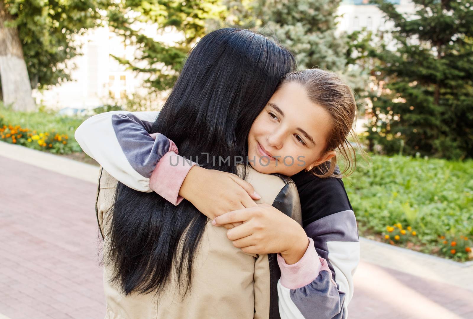 teen girl hugs mom in city park by raddnatt