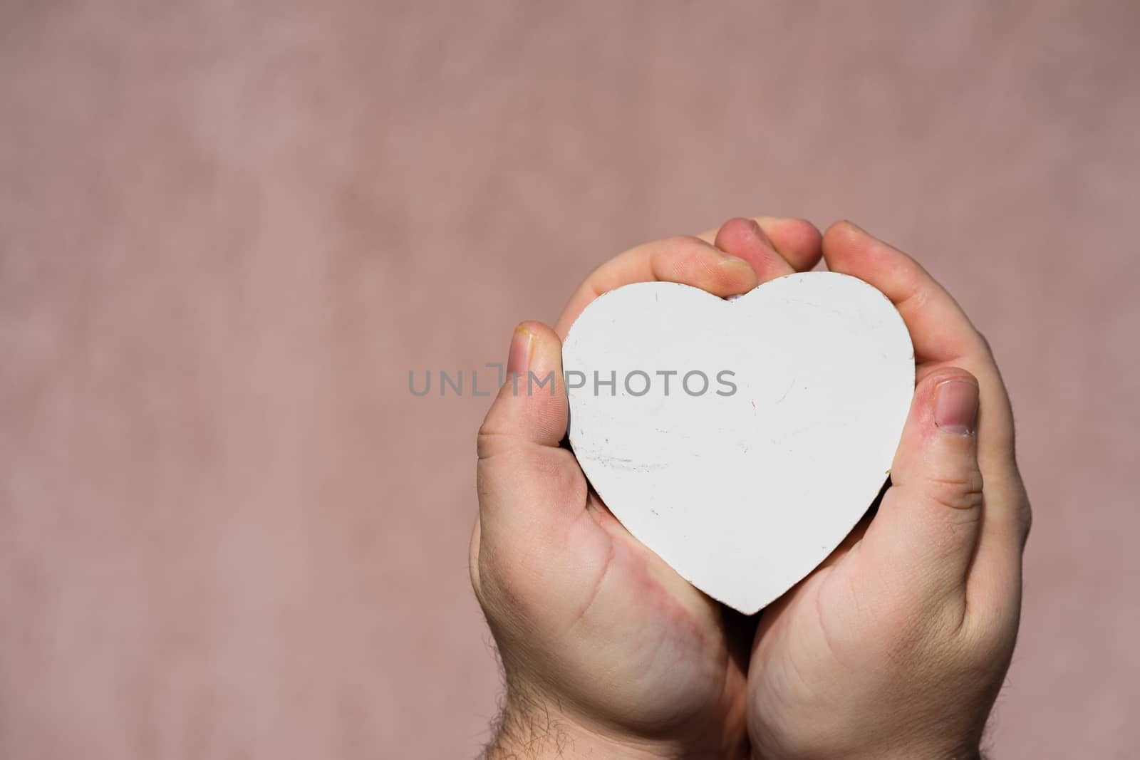 Hands holding a white wooden heart shaped object decoration isolated with copy space. Empty space template for your text.