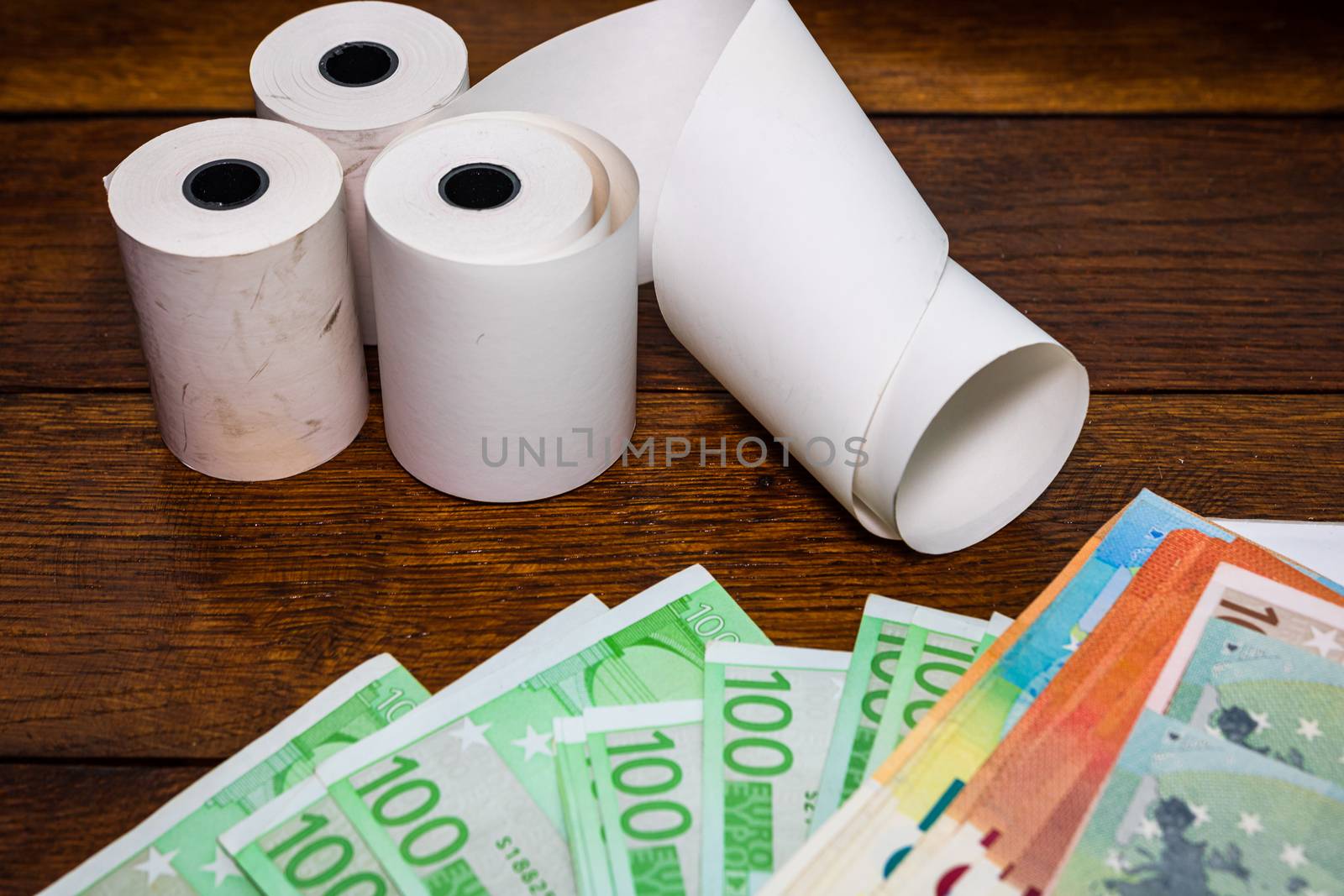 Roll of cash register tape and money isolated on table. Planning savings, spending money or business concept.