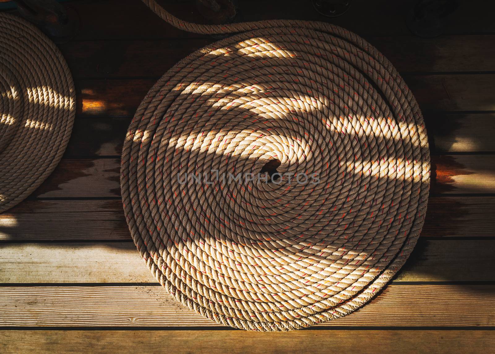 Sailboat nautical mooring rope curled into a circle on wooden deck