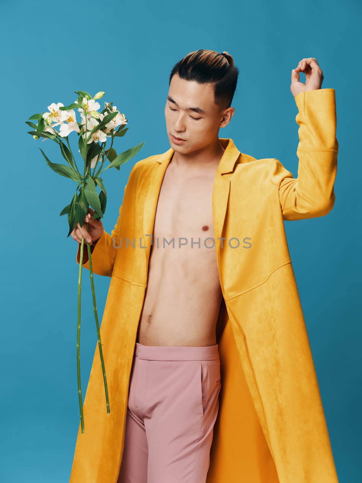 Romantic man with a bouquet of flowers on a blue background Asian model . High quality photo