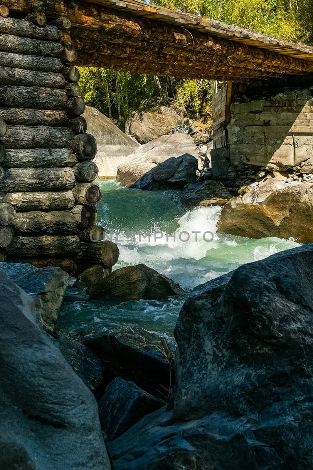 wooden bridge made of logs across a mountain river. by DePo