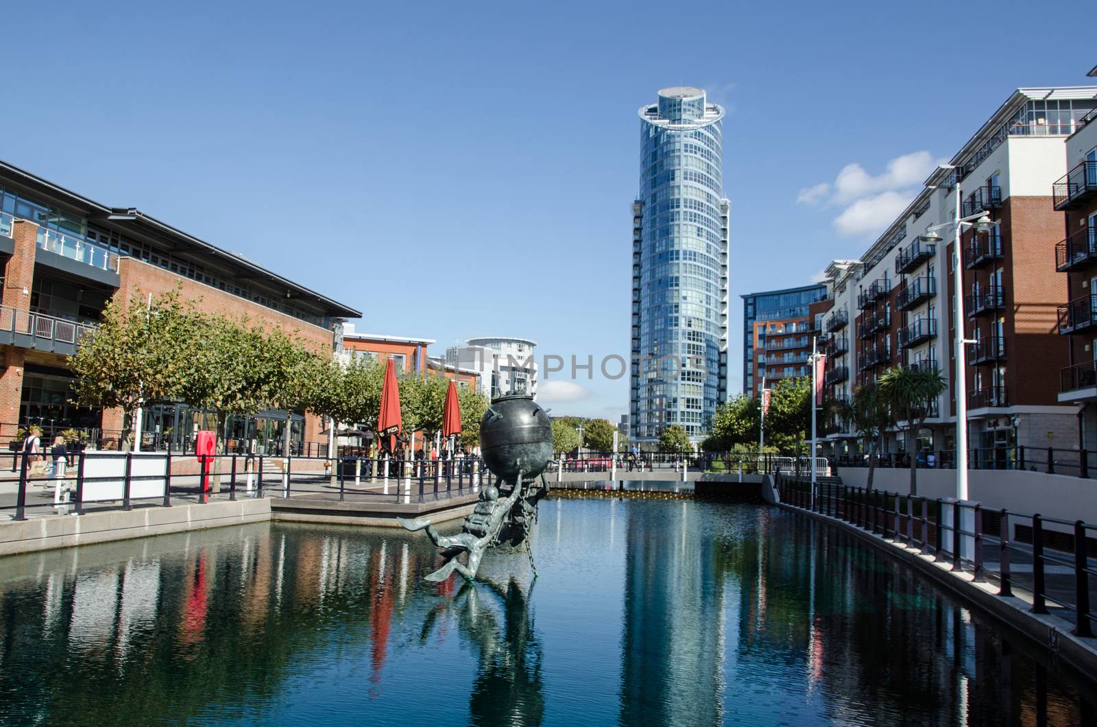 Portsmouth, UK - September 8, 2020: View along one of the converted docks at Gunwharf Quays, Portsmouth with the Vernon Monument to Royal Navy divers and bomb disposal operatives.