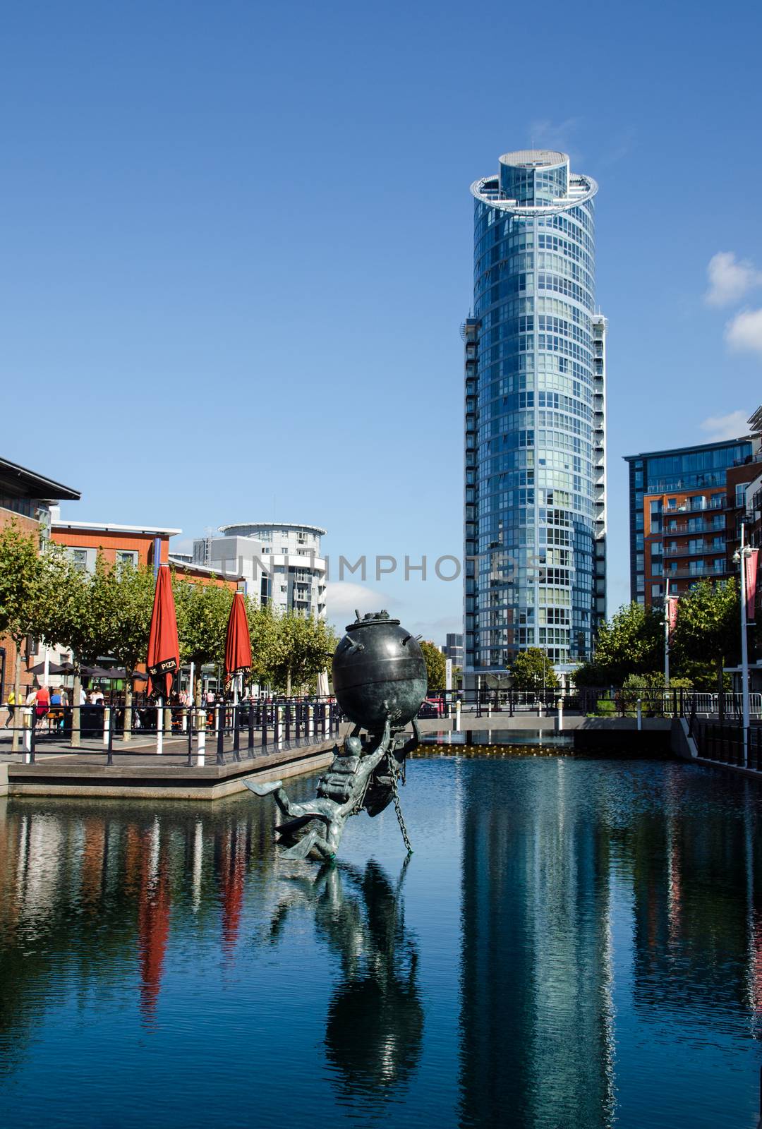 View along a converted dock looking towards the Number 1 Gunwharf Quays apartment block in Portsmouth, Hampshire.  The Vernon Monument to Royal Navy divers and bomb disposal experts is in the foreground.  Sunny Summer day.