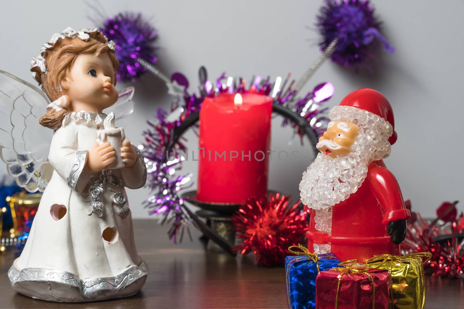 Christmas or new year's eve. Angel and Santa Claus with gifts at night on the background of a lit candle. New year holiday.