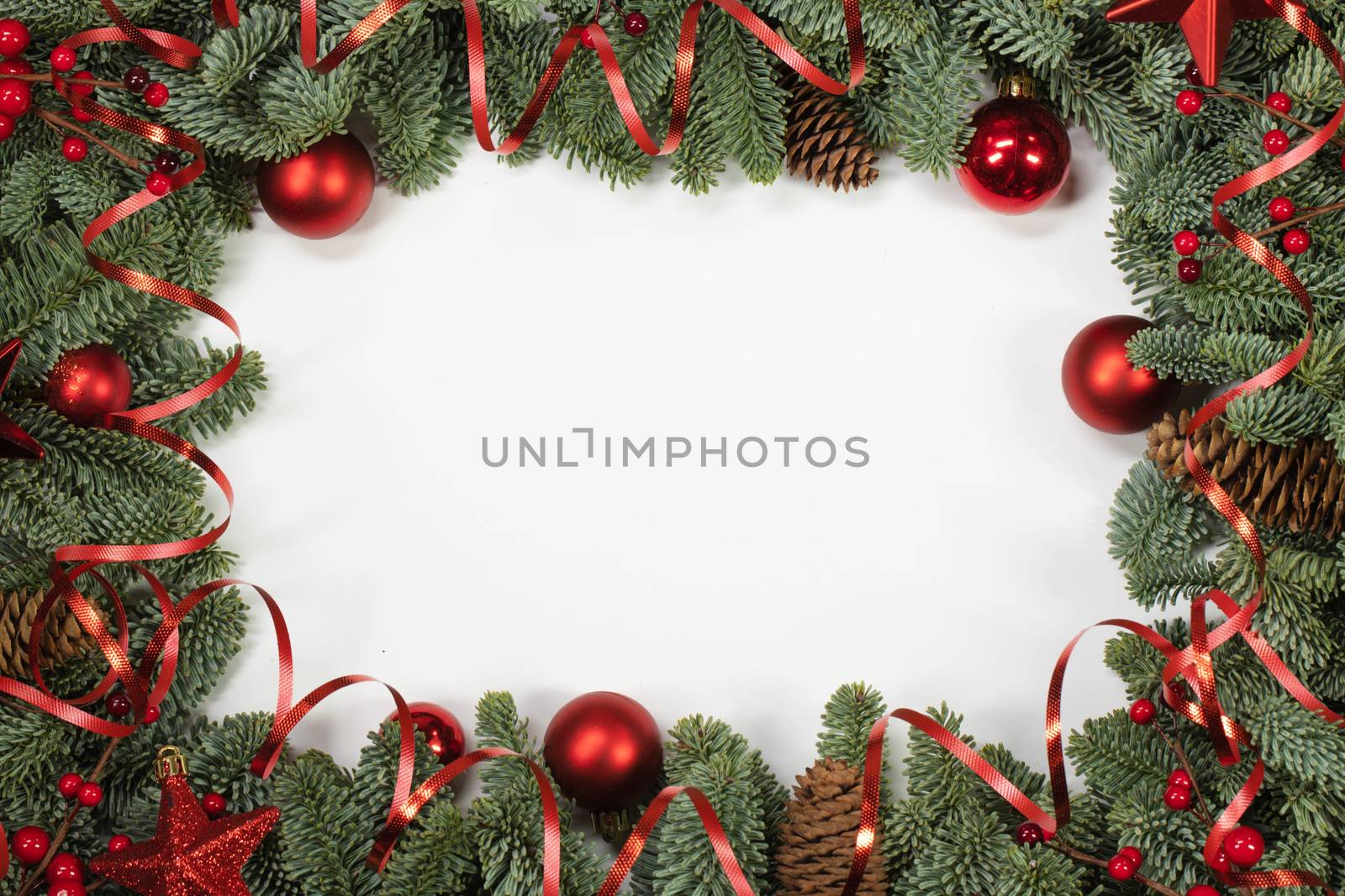 Christmas border frame design copmosition of noble fir tree branch and red decorations balls baubles pine cones isolated on white background