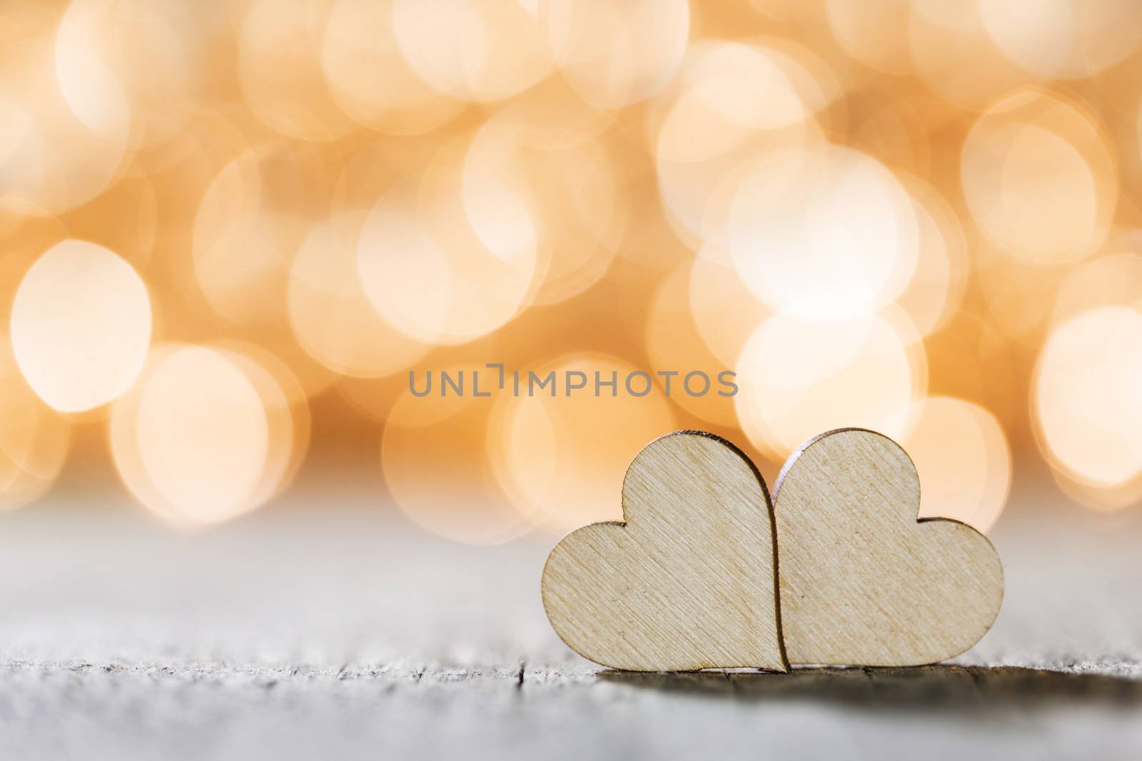 Two handmade wooden hearts on beautiful golden bokeh background. Vintage style. Love Valentine's Day concept.