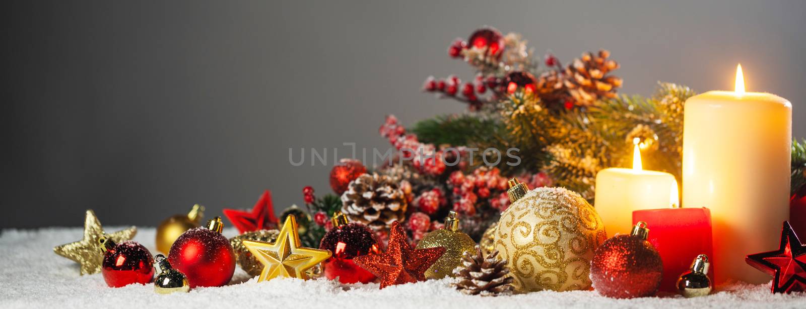 Christmas composition of colorful ornaments balls stars candles and fir tree branches on snow