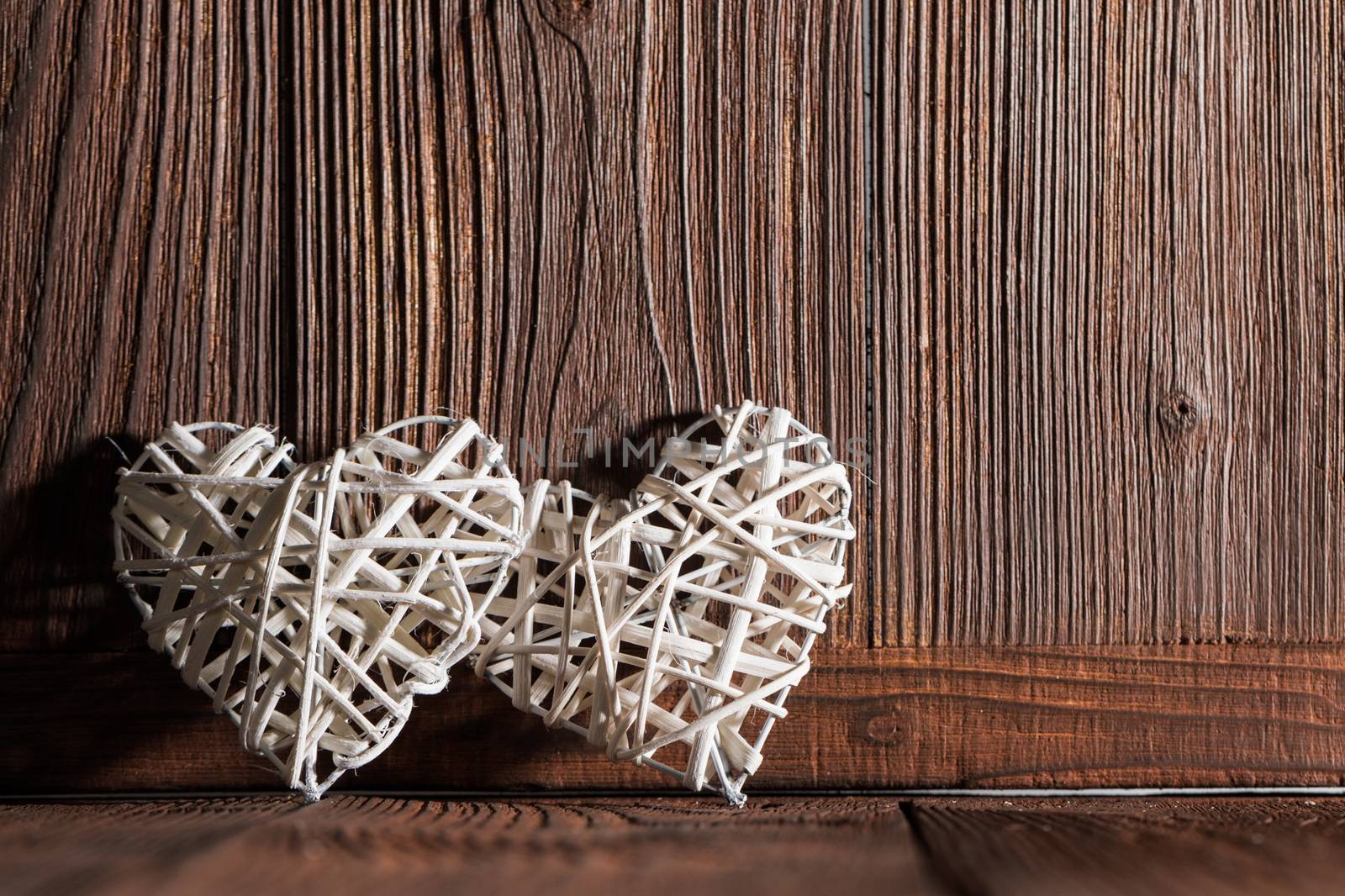 Two wicker hearts on wooden background with copy space for text