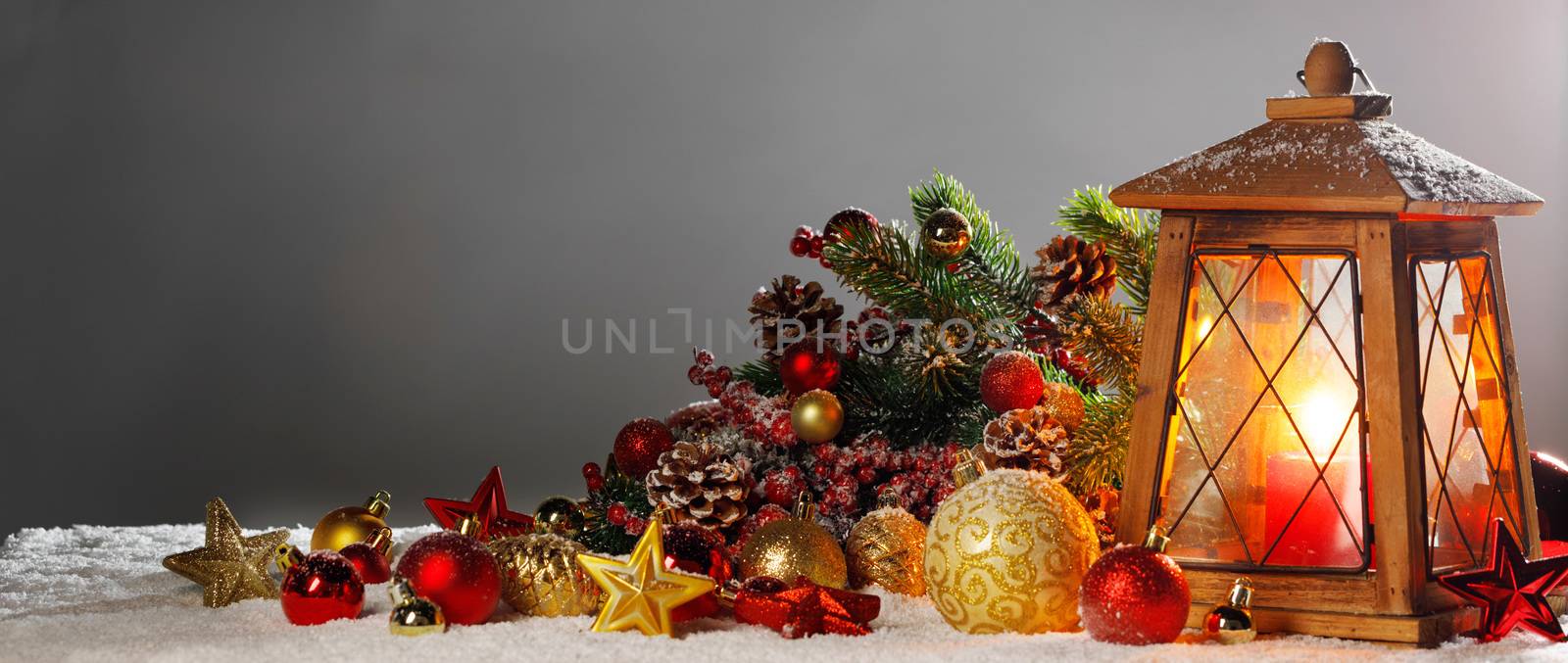 Christmas composition of lantern colorful ornaments balls stars candles and fir tree branches on snow