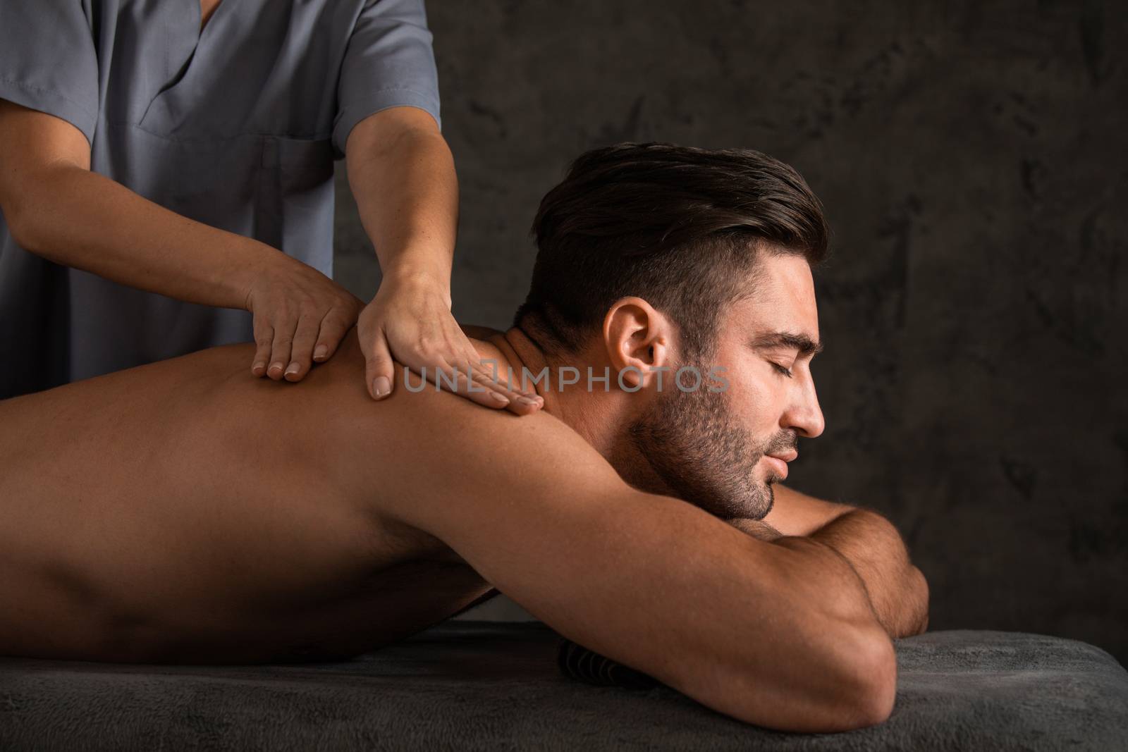 A good-looking man getting a back massage lying down at spa