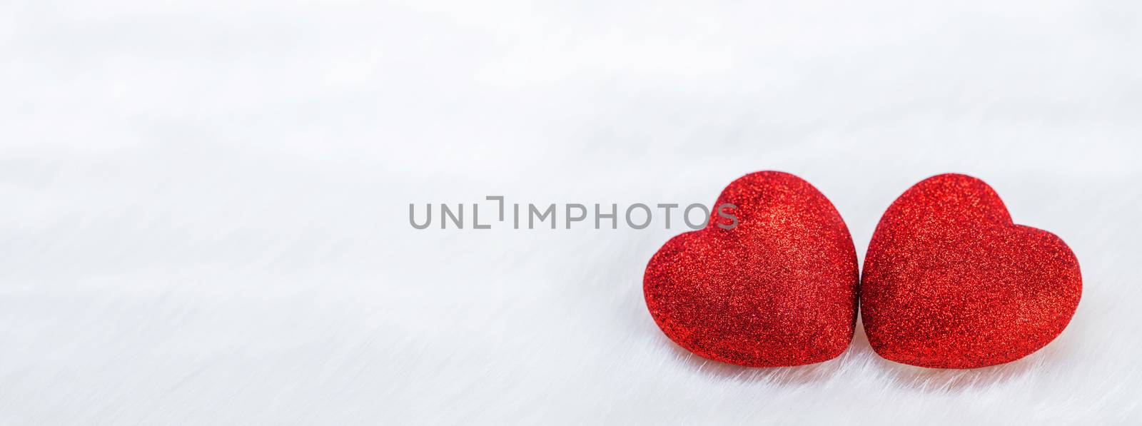 Two red glitter hearts symbol of love on white fur background, Saint Valentine Day celebration
