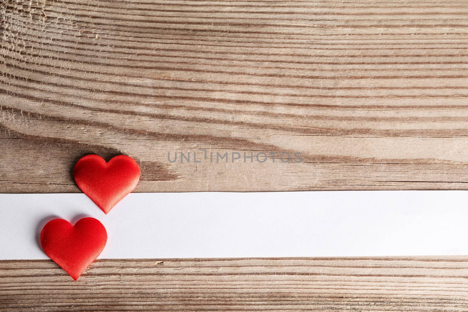 Valentine's day two red silk hearts and white paper on wooden background, love concept