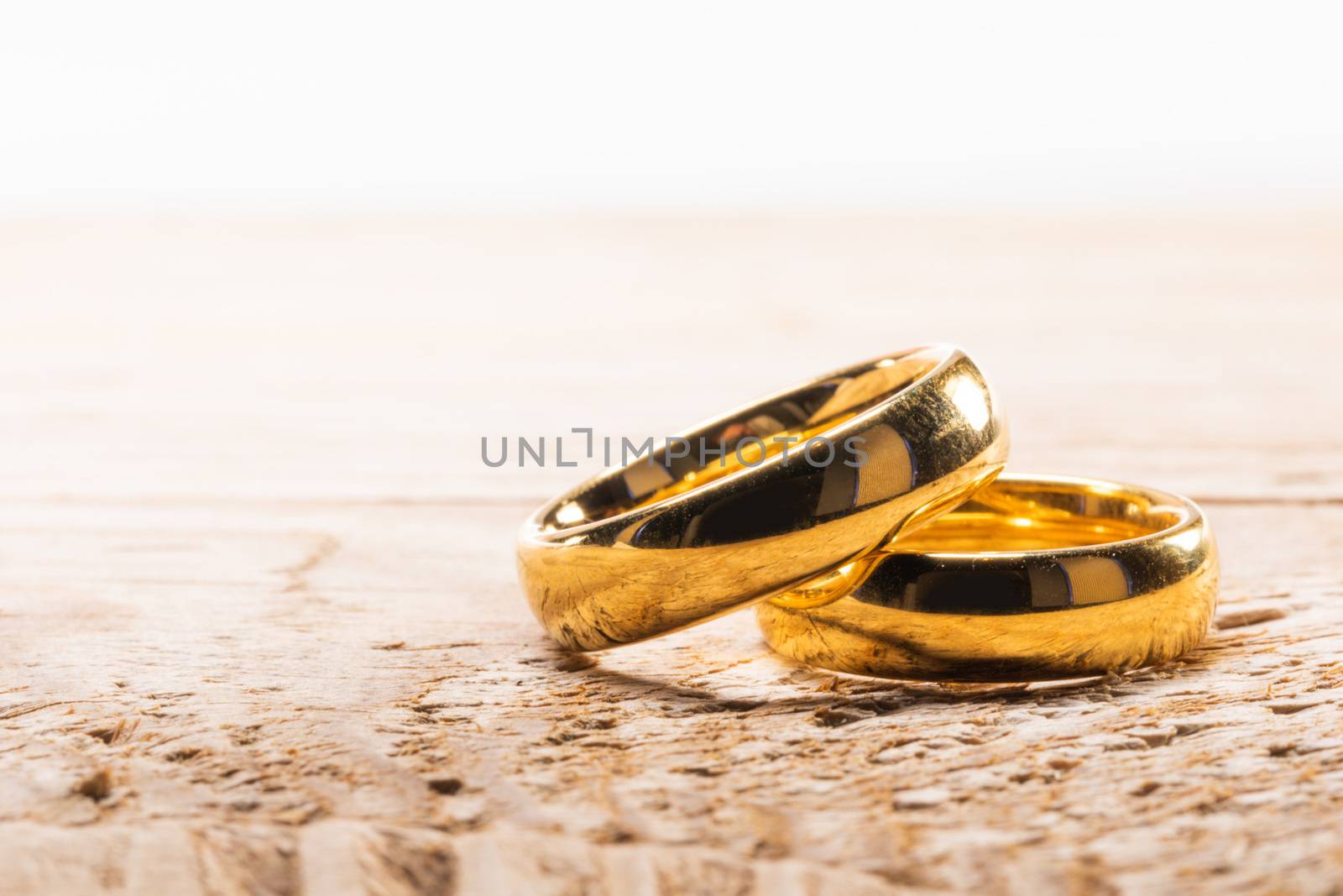 Two golden wedding rings on wooden background with copy space for text