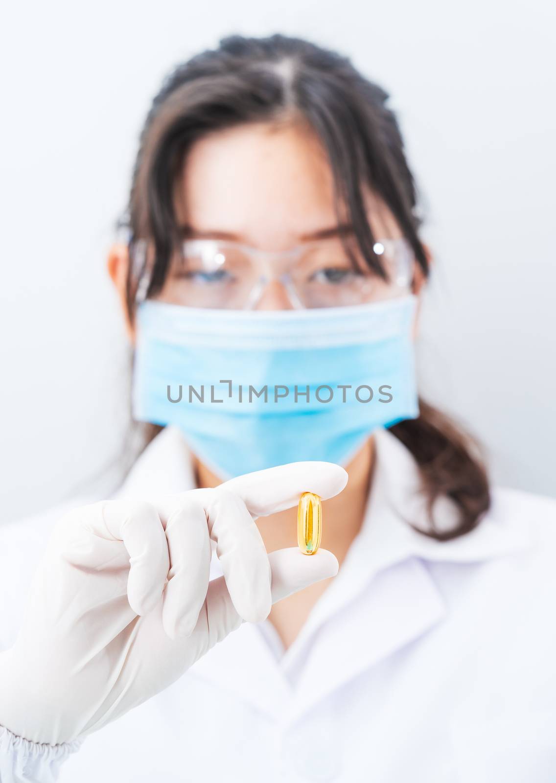 Close up Scientist hands putting in nitrile latex gloves holding Omega 3 capsule in labcoat wearing nitrile gloves, doing experiments in lab