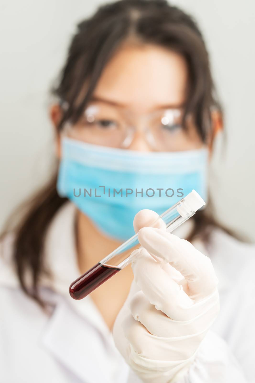 Technician scientist analyzing holding blood sample in test tube in laboratory for testing it on COVID, COVID-19, coronavirus virus analysis