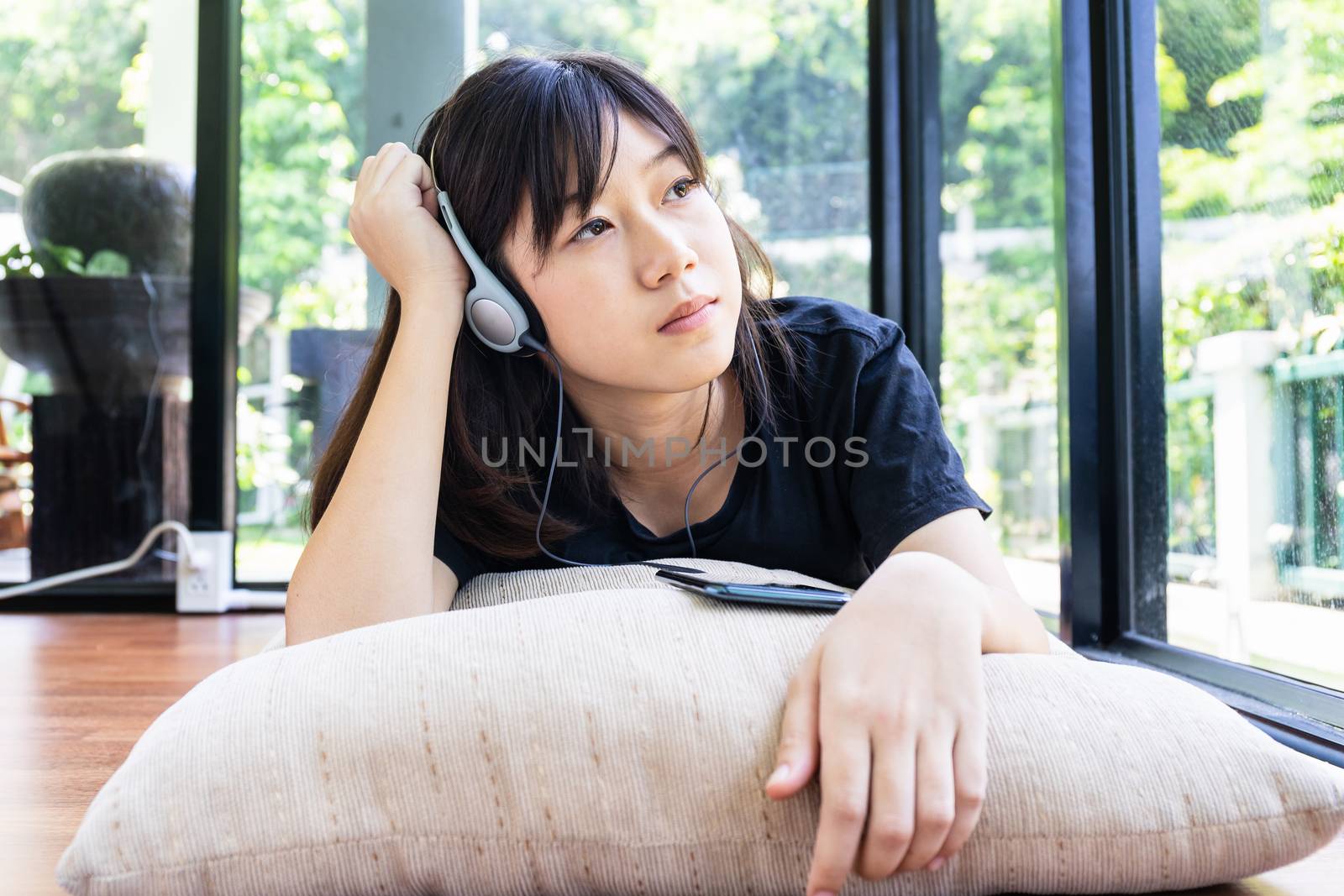 Teenage girl with headphones and listening to music from mobile phone at home