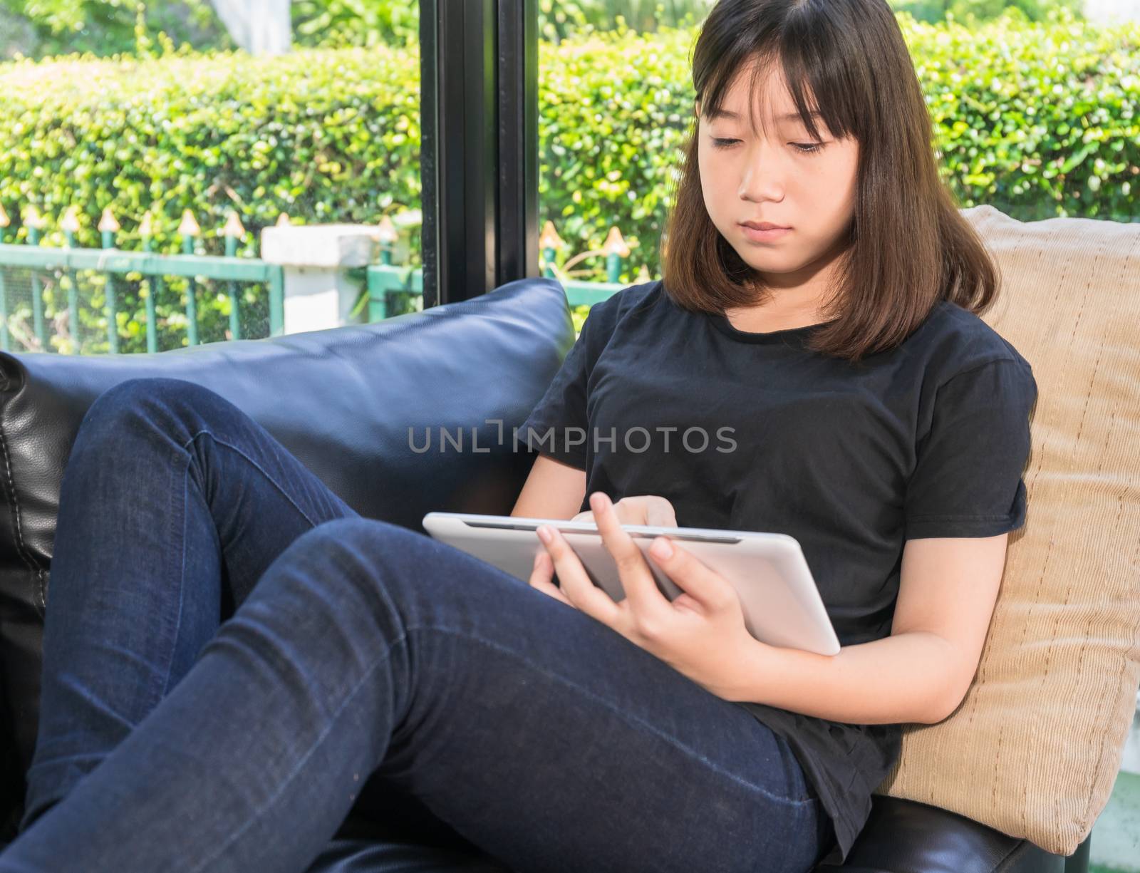 Young girl studying online from digital tablet in living room by stoonn