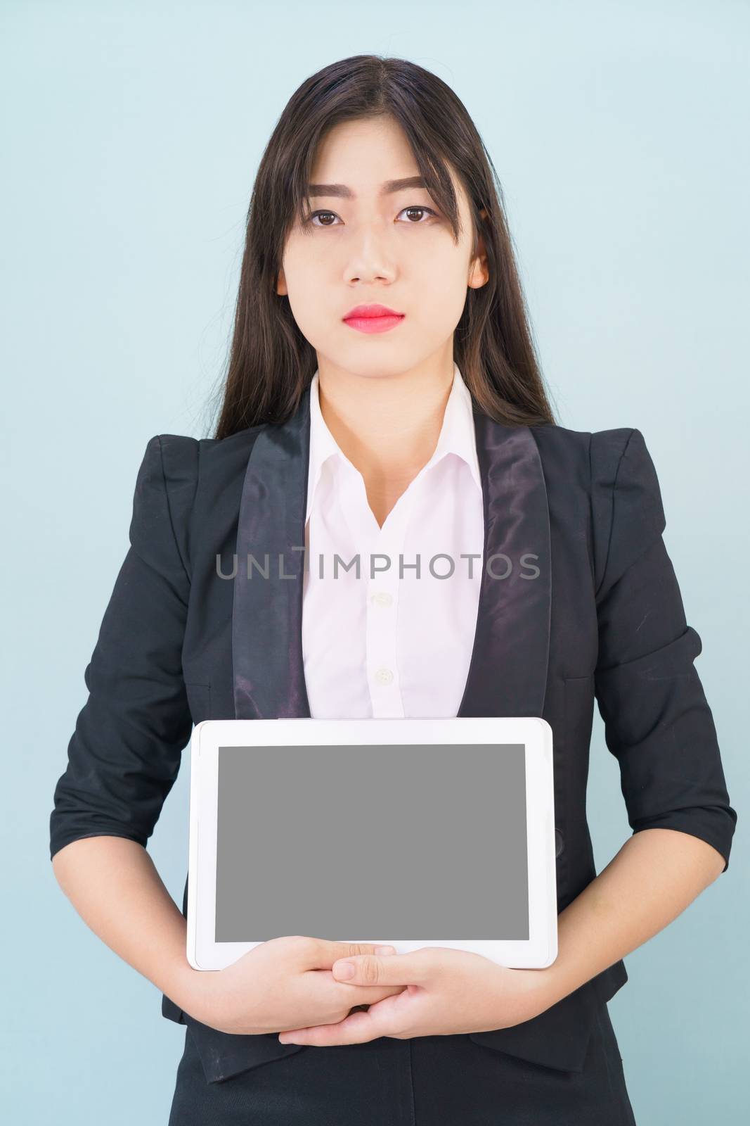 Young women in suit holding her digital tablet standing against blue background