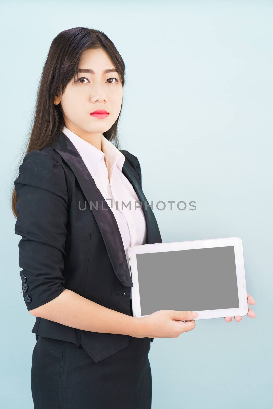 Young women in suit holding her digital tablet standing against blue background