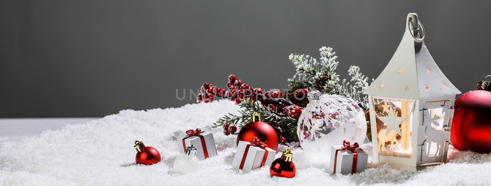 Christmas composition of lantern colorful ornaments balls stars candles and fir tree branches on snow
