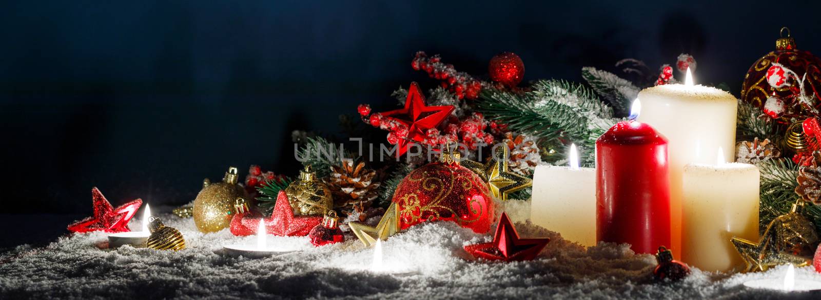 Christmas composition of colorful ornaments balls stars candles and fir tree branches on snow