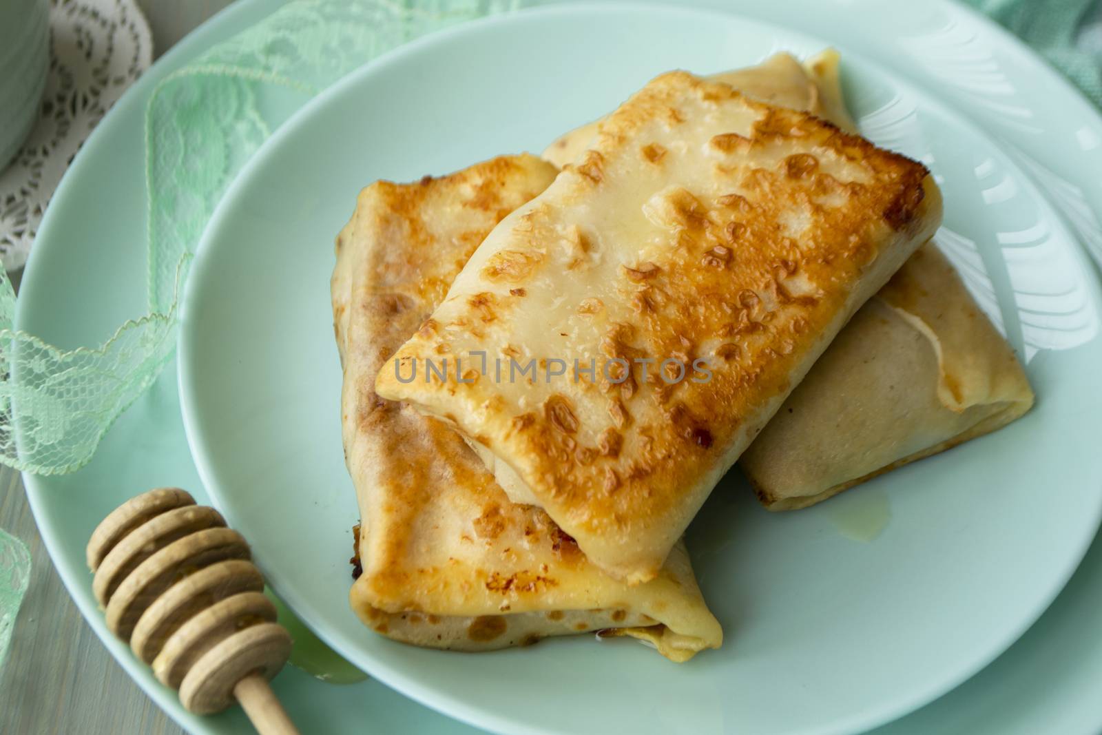 Crepes stuffed with apple on turquoise plate close up