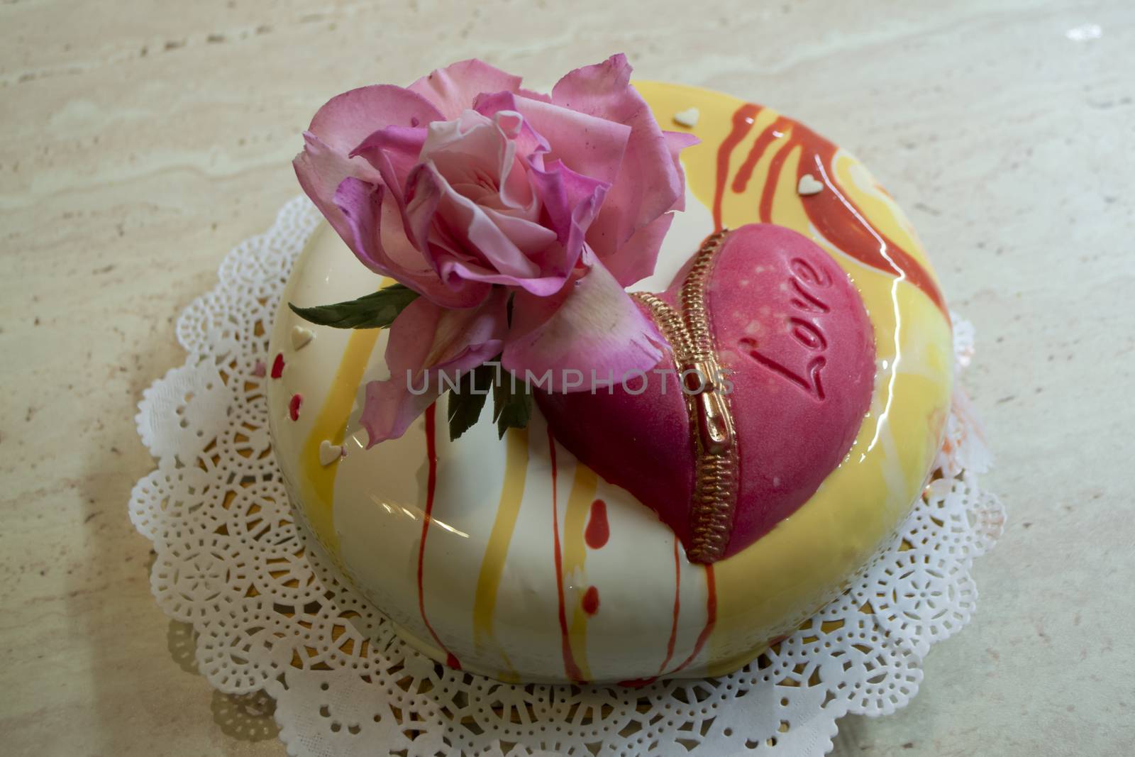 Contemporary mousse cake covered with mirror glaze with edible sugar rose and chocolate heart