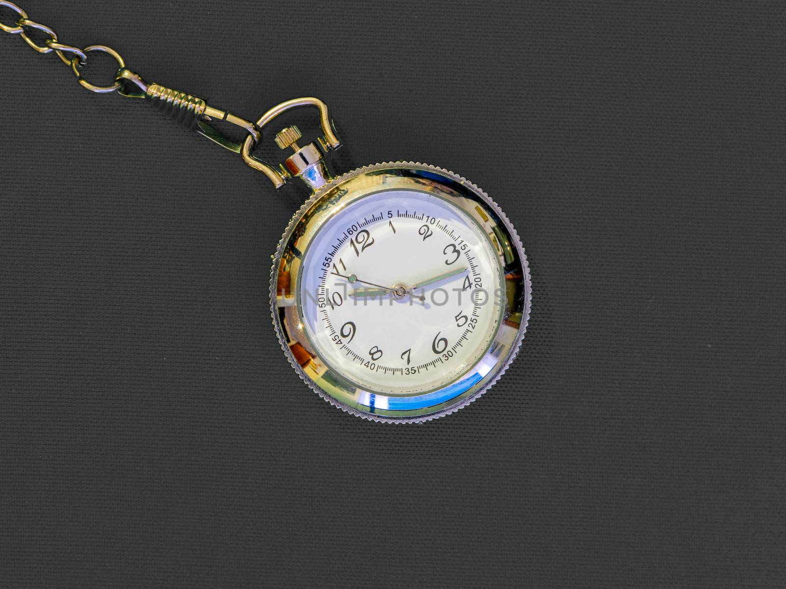 Small steel pocket watch with white dial, metal object on gray uniform background