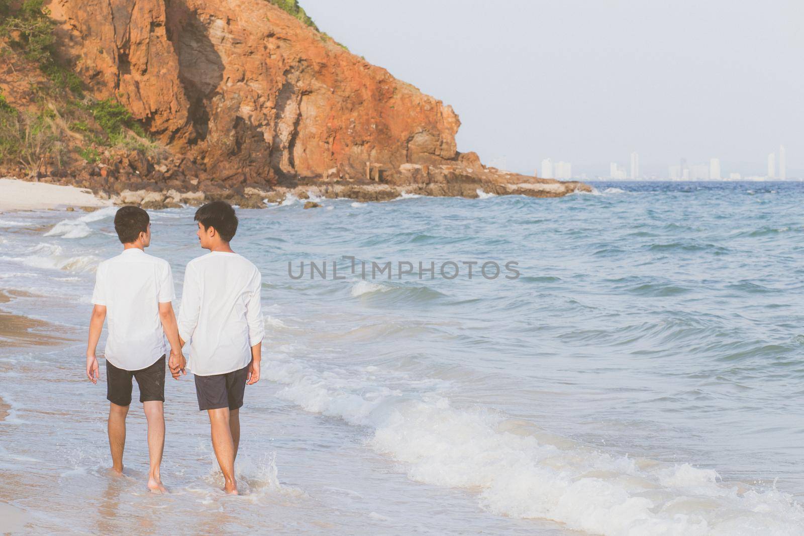 Back view homosexual portrait young asian couple walking with cheerful together on beach in summer, asia gay going tourism for leisure and relax with happiness in vacation at sea, LGBT legal concept. by nnudoo