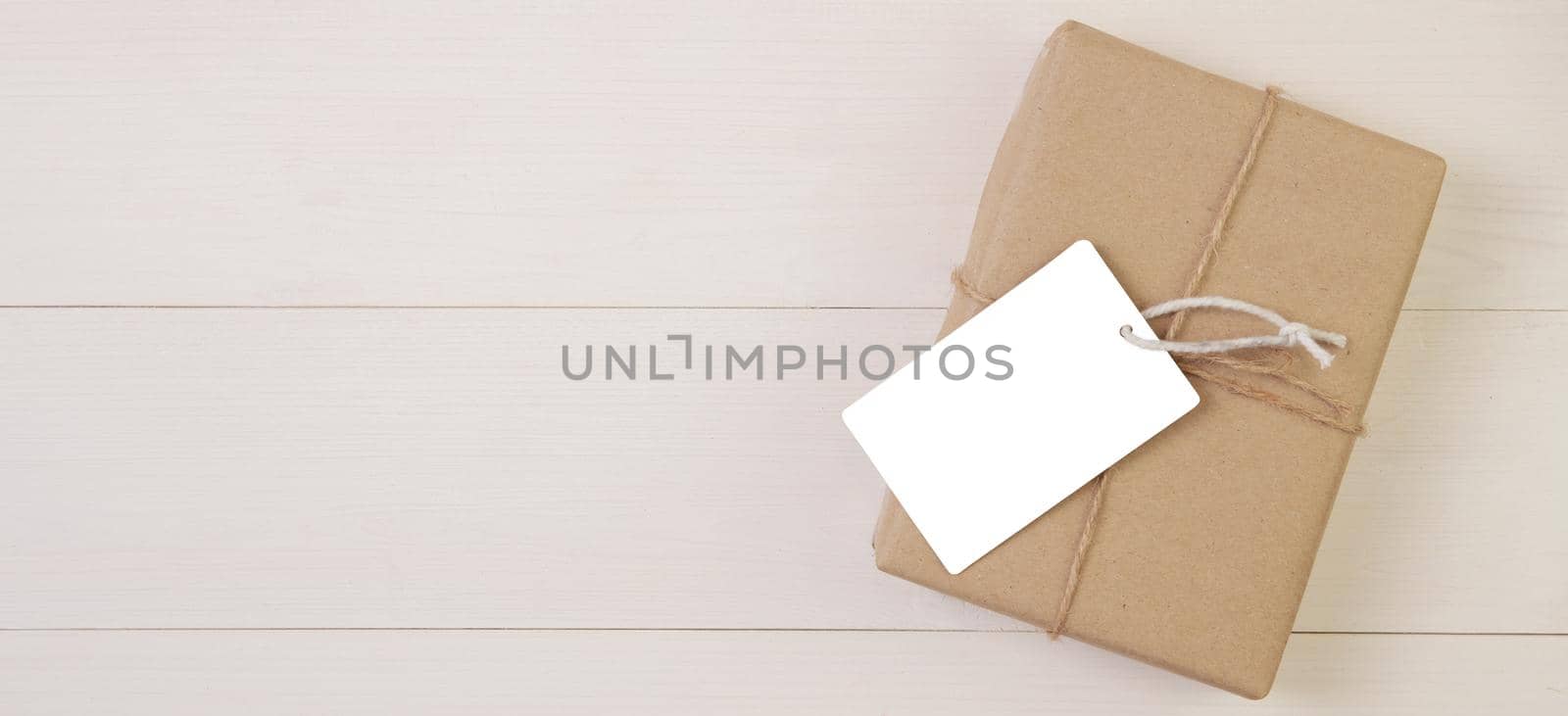 Gift box and tag on wooden background with romantic, presents for mother day or valentine day with pastel tone, package with congratulation, nature on desk, holiday concept, banner website. by nnudoo