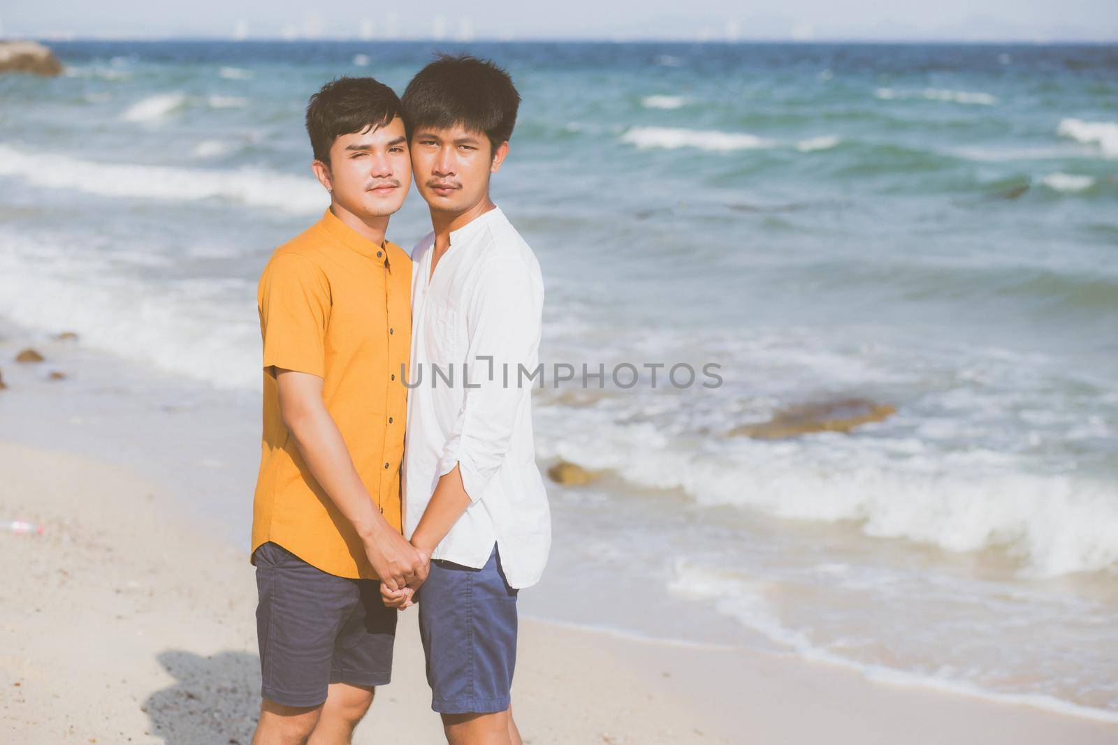 Homosexual portrait young asian couple standing together on beach in summer, asia gay holding hands going sea for leisure and relax with romantic and happy in vacation at sea, LGBT with legal concept. by nnudoo