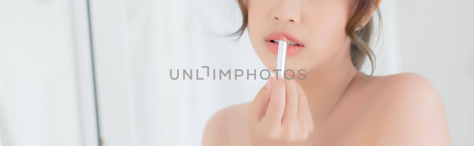 Beautiful portrait young asian woman looking mirror applying makeup lipstick at room, beauty lips asia girl makeup and cosmetic fashion, lifestyle and health care concept, banner website. by nnudoo