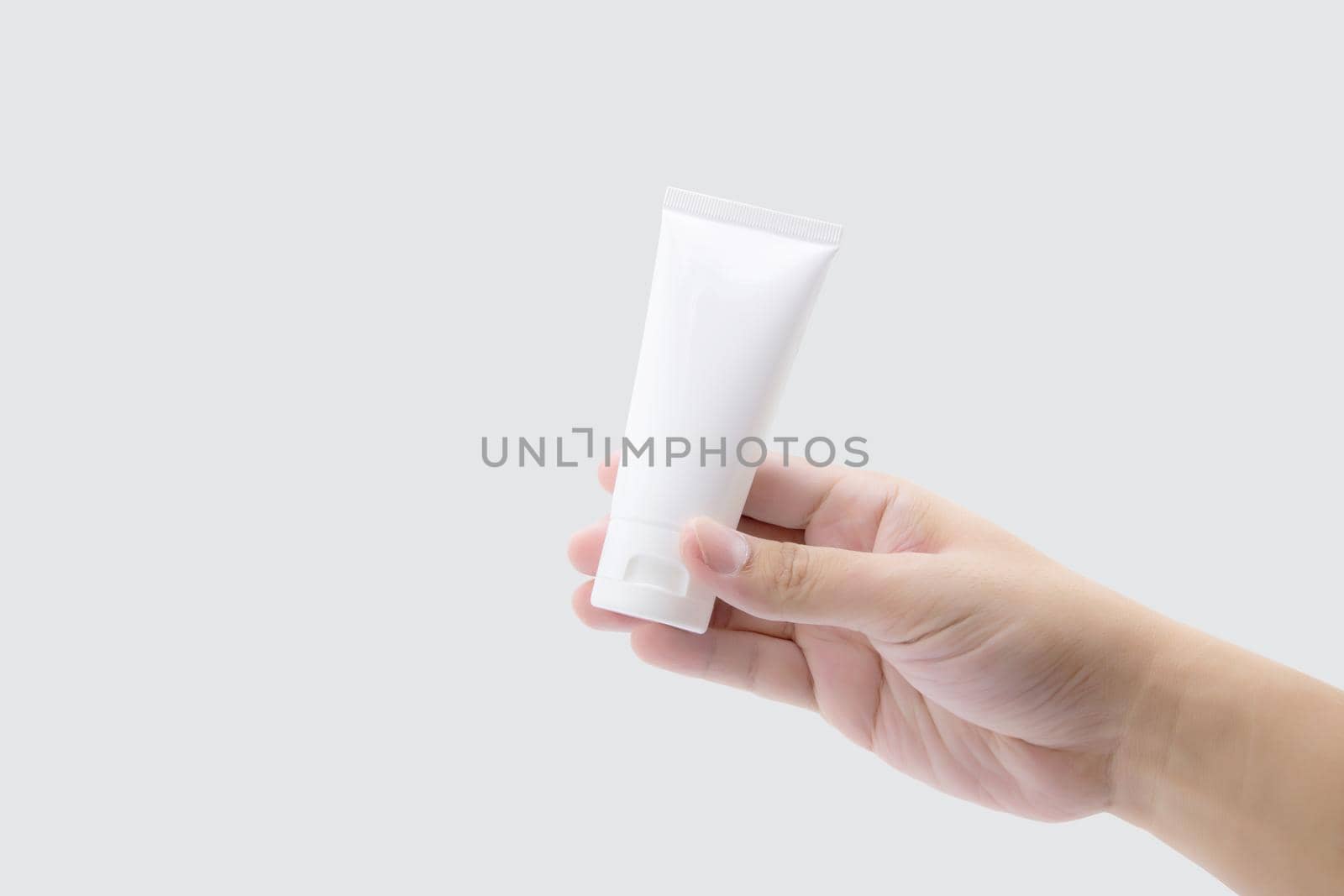 Hand of man holding mockup product about cream or lotion in tube isolated on white background, face foam, alcohol gel, skin care, package of treatment and moisturizing, design and presentation.