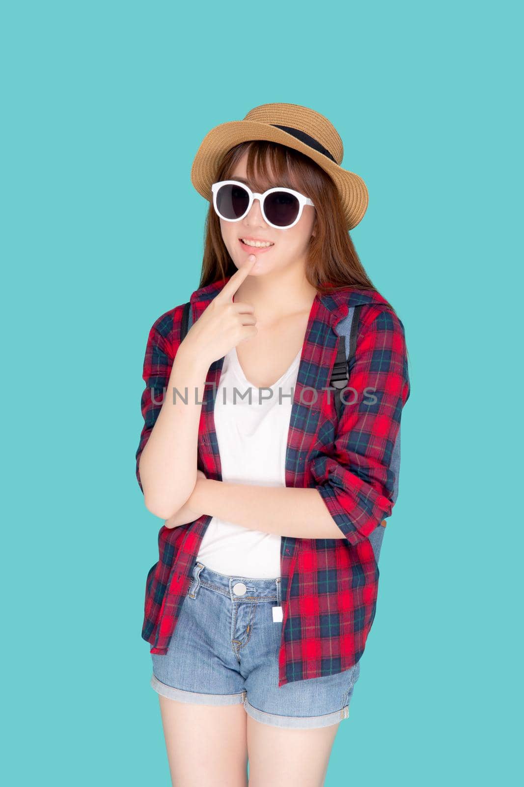 Beautiful portrait young asian woman wear sunglasses and hat having backpack smile confident enjoy summer holiday isolated blue background, tourist model girl thinking idea planning travel concept.