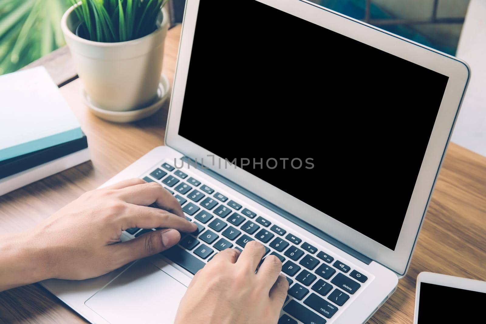 Hand of man working laptop computer with blank screen, work from home for social distracting is new normal, freelance using notebook with display empty on workspace, business and communication concept.