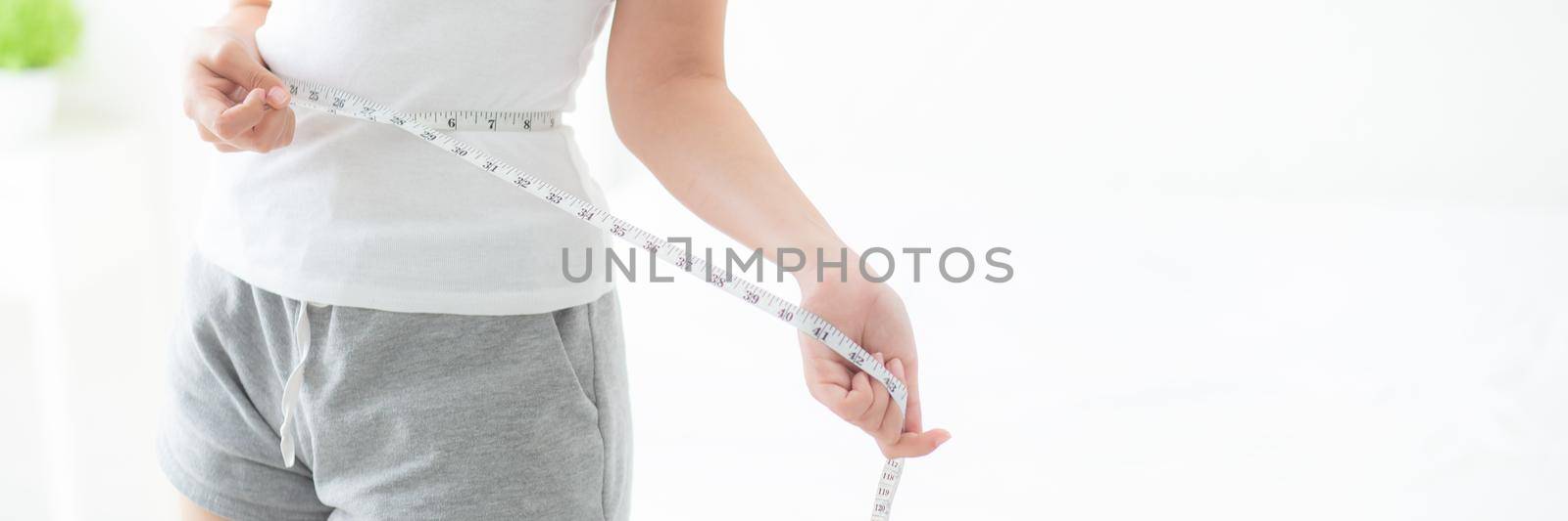 Beautiful young asian woman body diet and slim with measuring waist for weight in the bedroom, girl have cellulite and calories loss with tape measure, health and wellness concept, banner website.