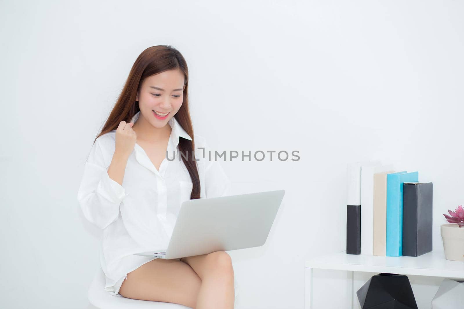 Beautiful of portrait happy young asian woman using laptop work with success on chair in the home, girl and notebook shopping online with glad, communication concept. by nnudoo