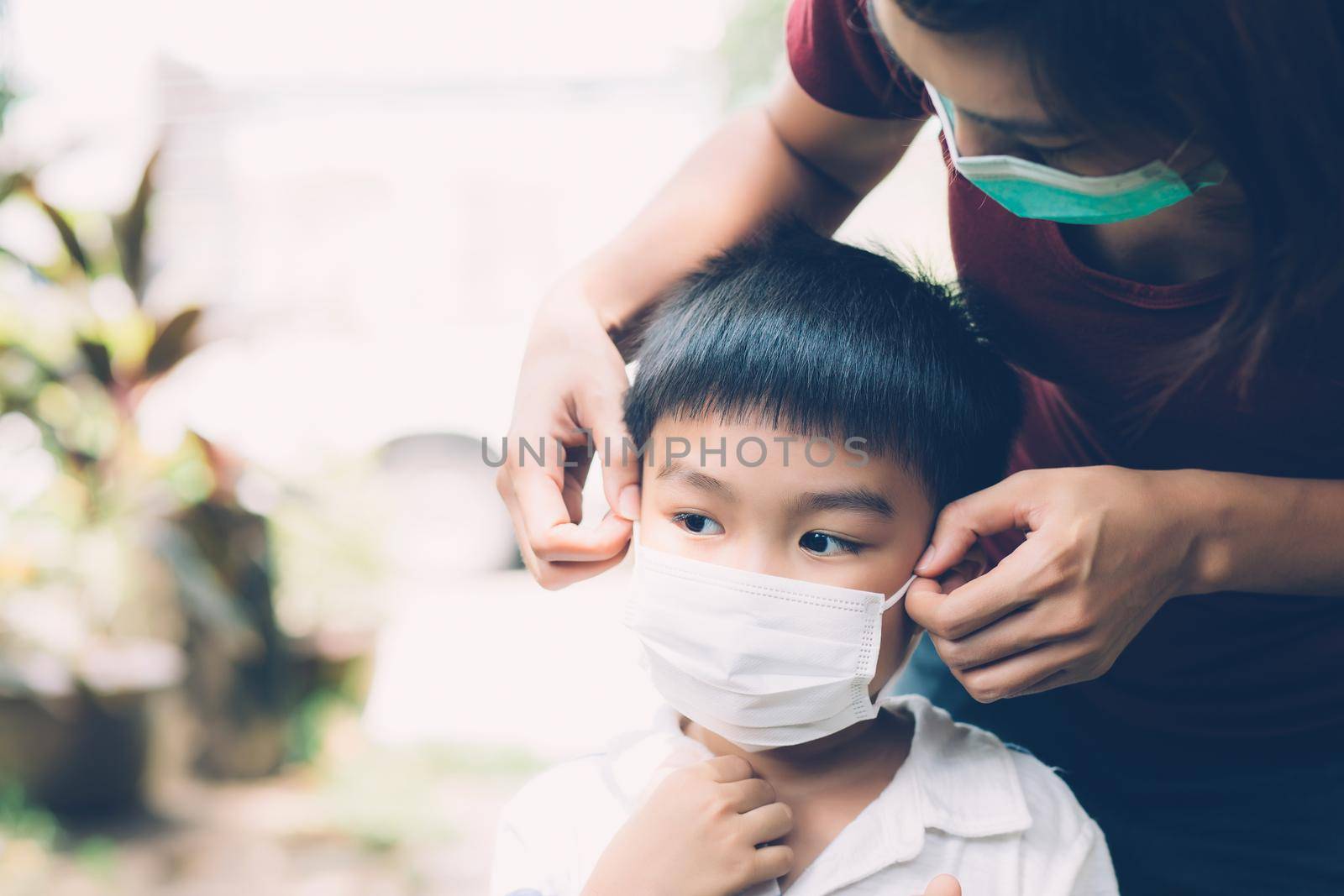 Mother take care son with face mask for protection disease flu or covid-19 outdoors, mom wearing on medical mask with child safety for protect outbreak of pandemic in public, medical concept. by nnudoo