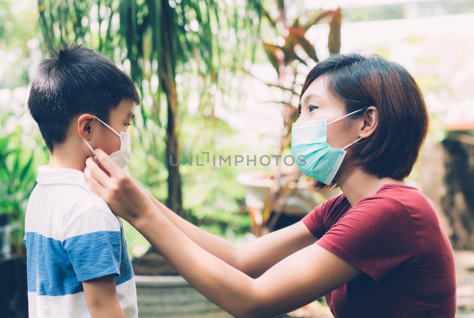 Mother take care son with face mask for protection disease flu or covid-19 outdoors, mom wearing on medical mask with child safety for protect outbreak of pandemic in public, medical concept. by nnudoo