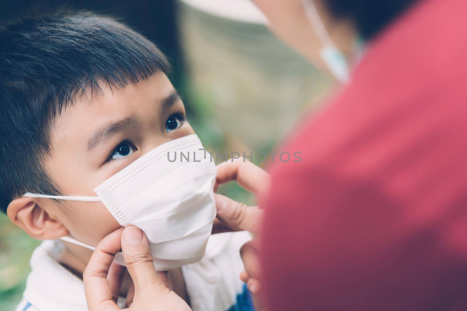 Mother take care son with face mask for protection disease flu or covid-19 outdoors, mom wearing on medical mask with child safety for protect outbreak of pandemic in public, medical concept. by nnudoo