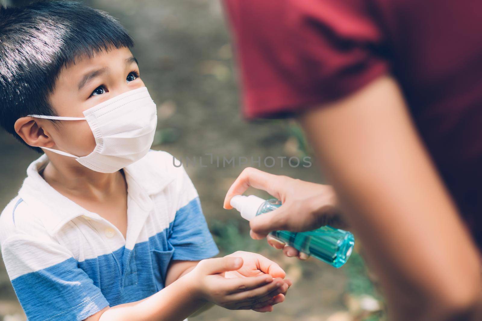 Mother take care son with face mask and sanitizer for protection disease flu or covid-19 outdoors, mom and child wearing medical mask clean hand for safety for outbreak of pandemic in public. by nnudoo