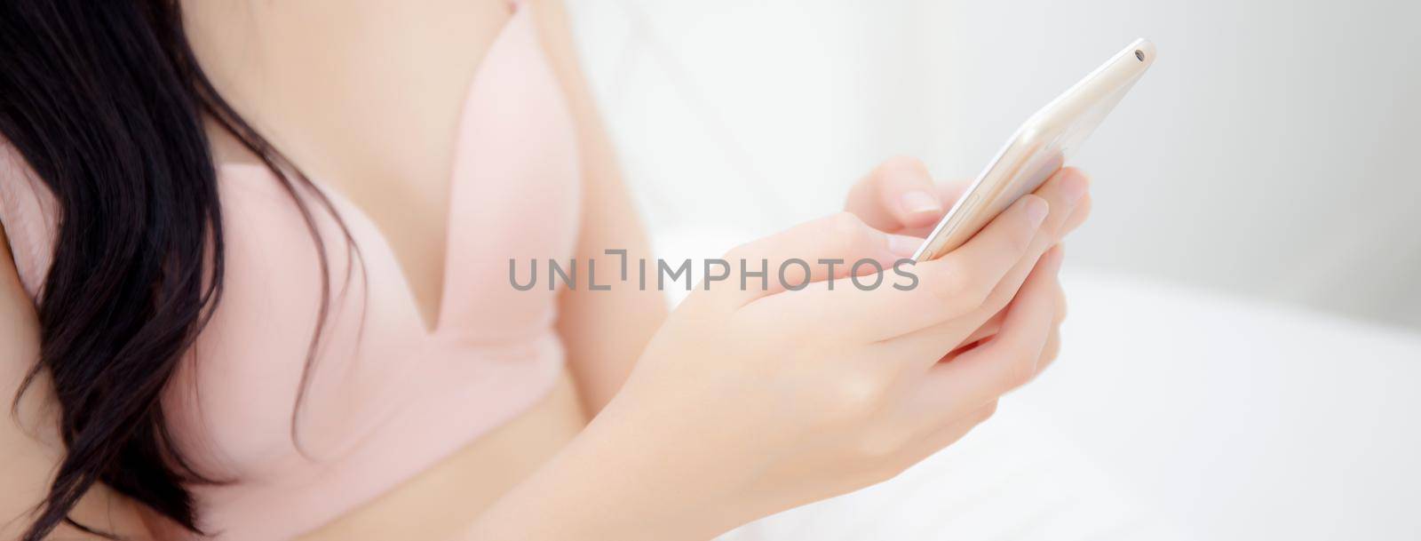 Closeup beautiful young asian woman sexy in underwear chatting on mobile phone in the bedroom, girl looking social media on smartphone for relax, communication and lifestyle concept, banner website. by nnudoo