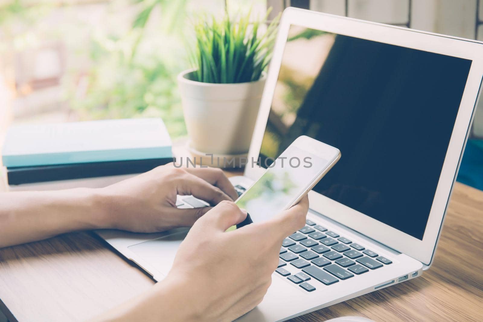 Hand of business man working from home using laptop computer to internet online on desk, lifestyle of new normal, social distancing, freelance work in stay home and look phone, communication concept.