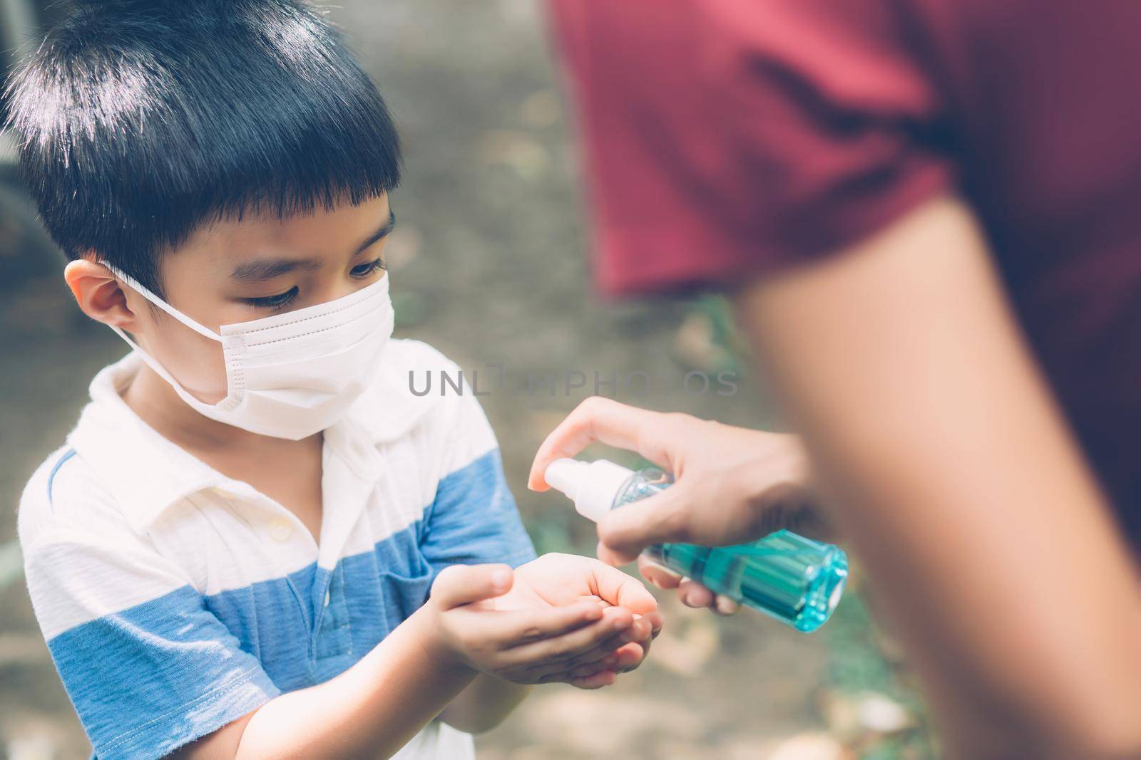 Mother take care son with face mask and sanitizer for protection disease flu or covid-19 outdoors, mom and child wearing medical mask clean hand for safety for outbreak of pandemic in public. by nnudoo