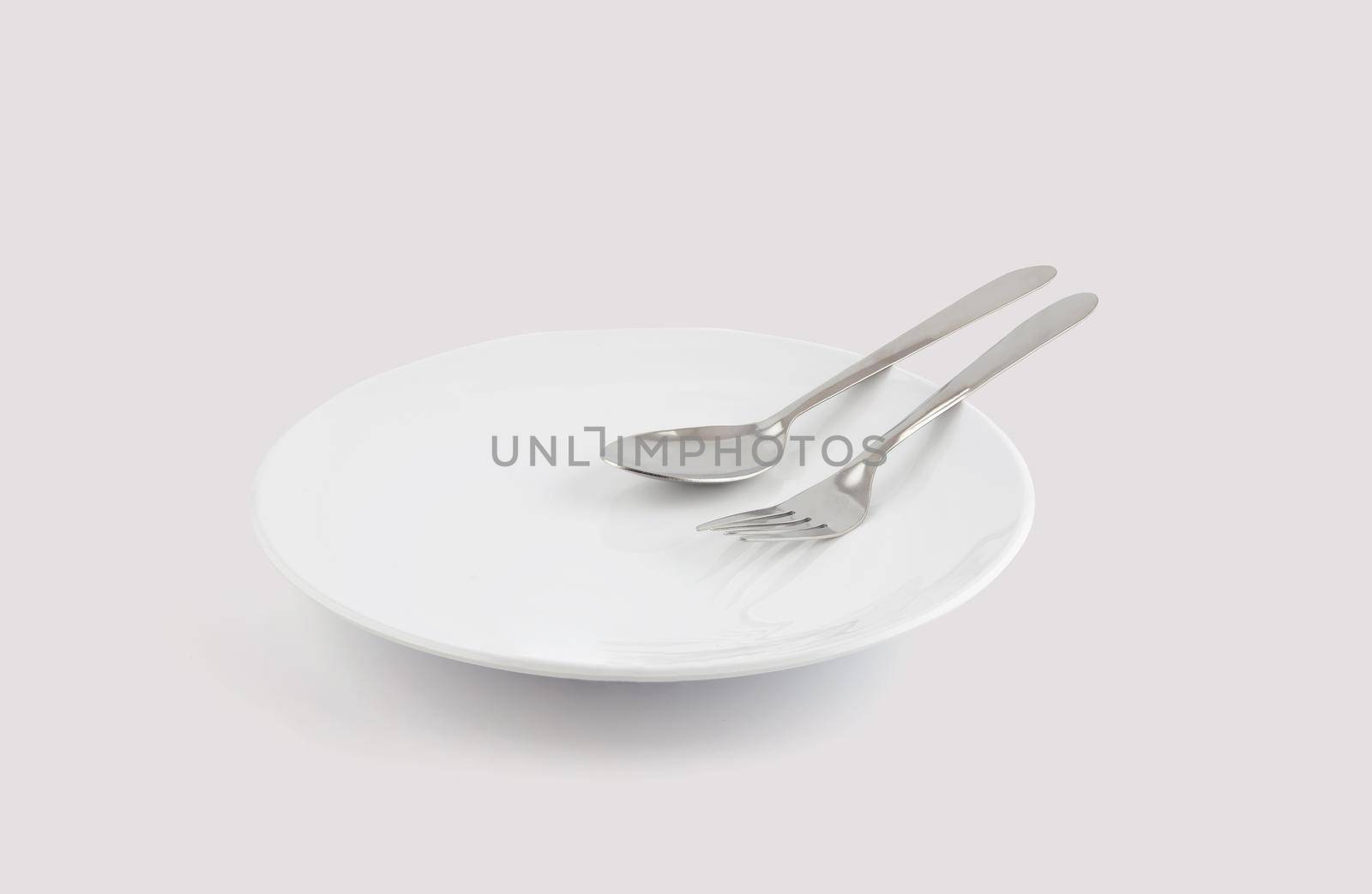 Dish spoon and fork isolated on white background, utensil for food, ceramic plate with empty, kitchenware or dishware with stainless in studio, object concept.