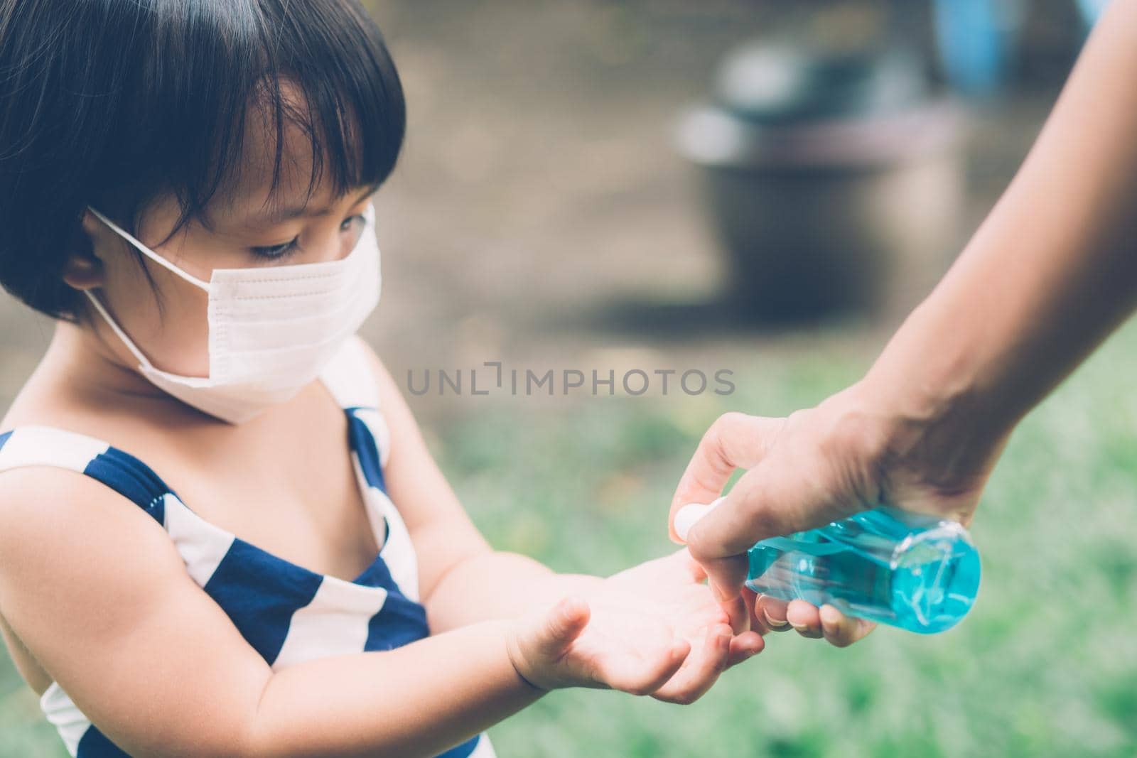 Mother take care son with face mask and sanitizer for protection disease flu or covid-19 outdoors, mom and child wearing medical mask clean hand for safety for outbreak of pandemic in public.